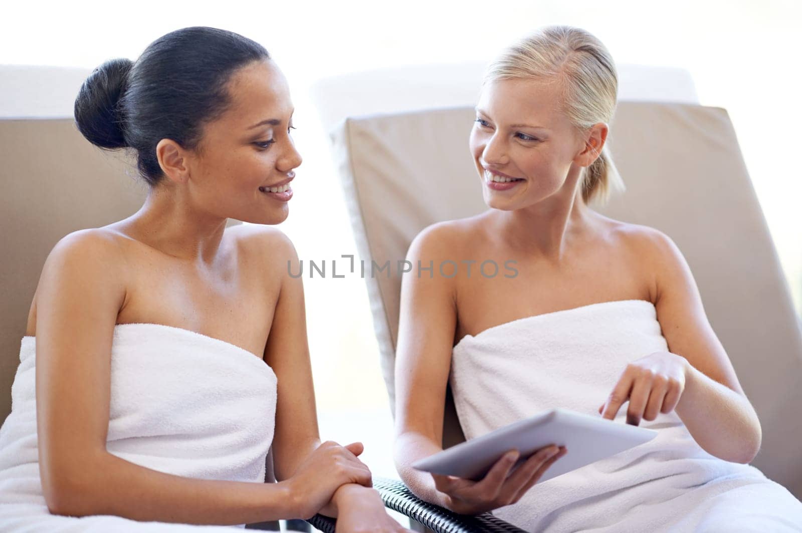 Deciding which beauty treatments to get. two young women looking at a magazine in a beauty spa