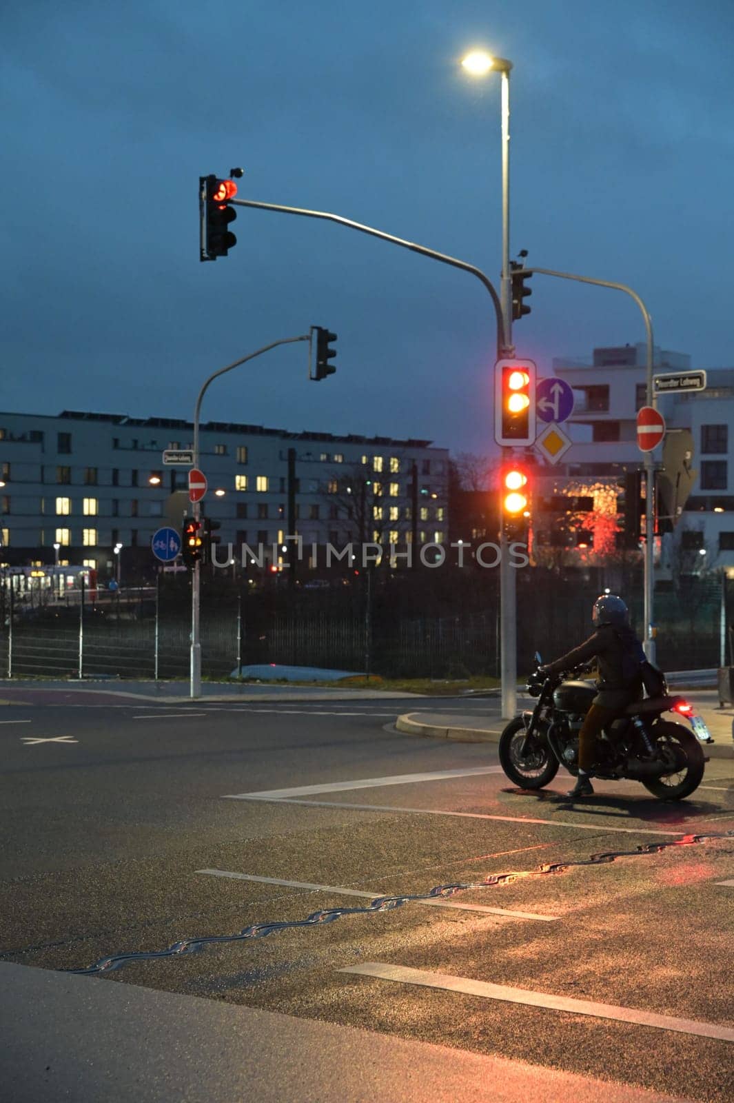 Motorcyclist with retro motorcycle standing in front of a green traffic light in Heerdt