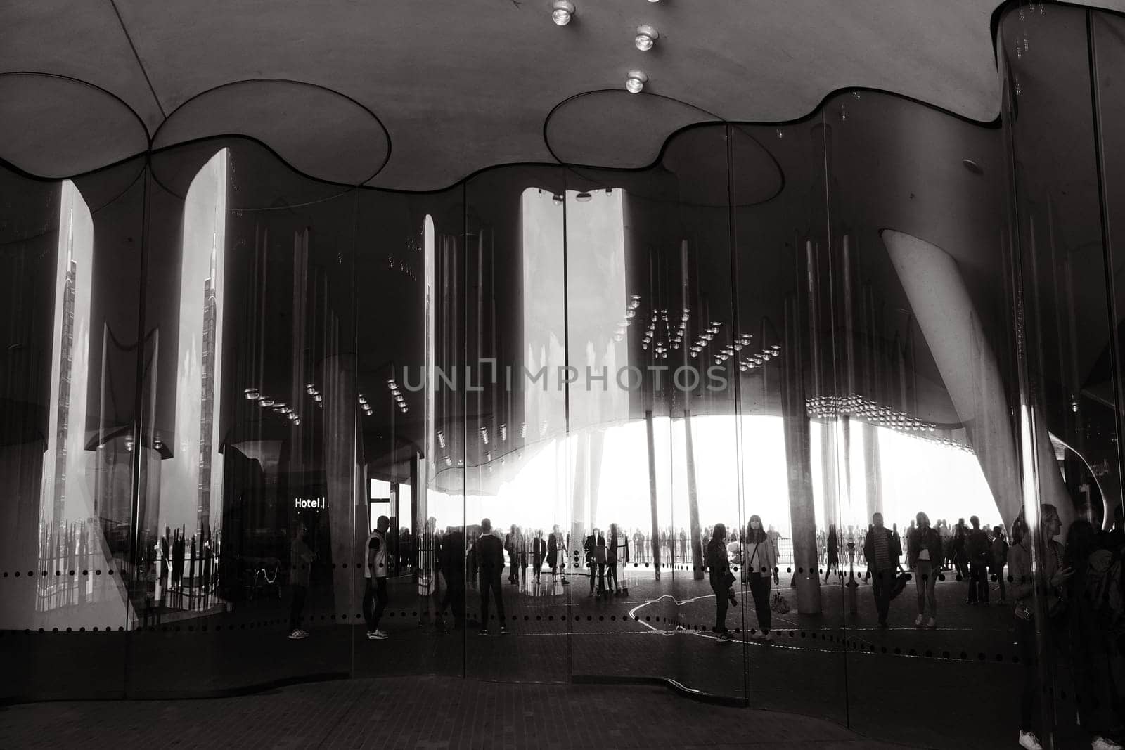 Grayscale view of people reflection on the curved wavy mirror facade on Elbphilharmonie in Hamburg, Germany