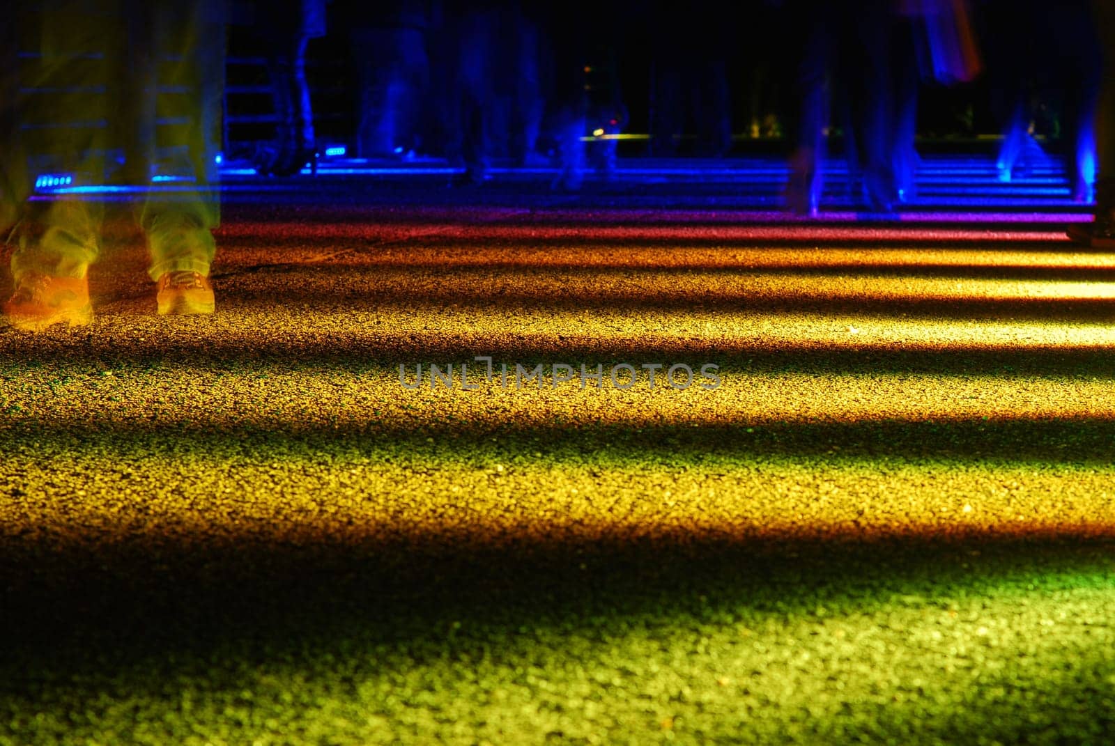 Long exposure shot of feet walking on an illuminated rainbow road in Essen, Germany