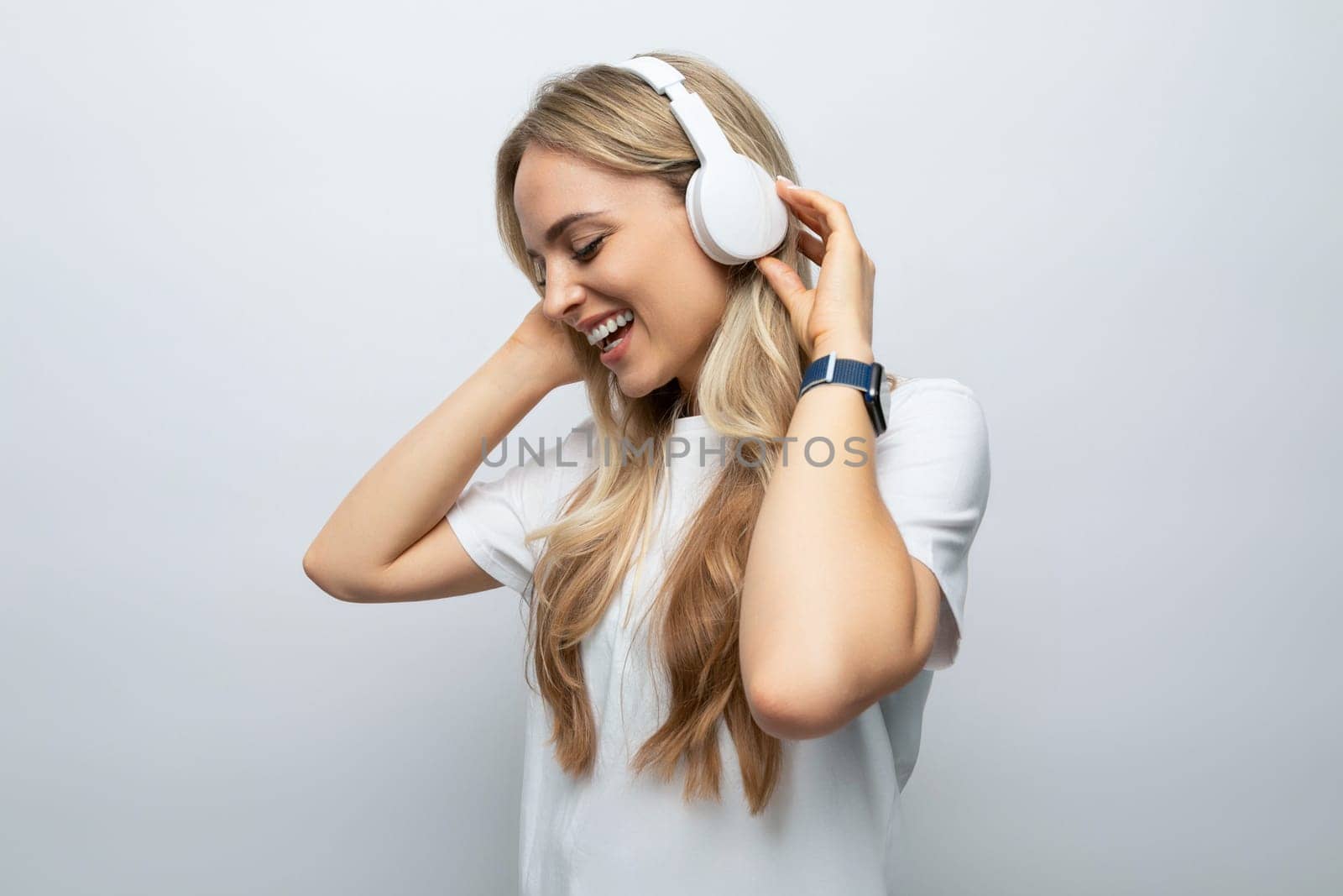 romantic woman sings along to music from headphones among white background by TRMK