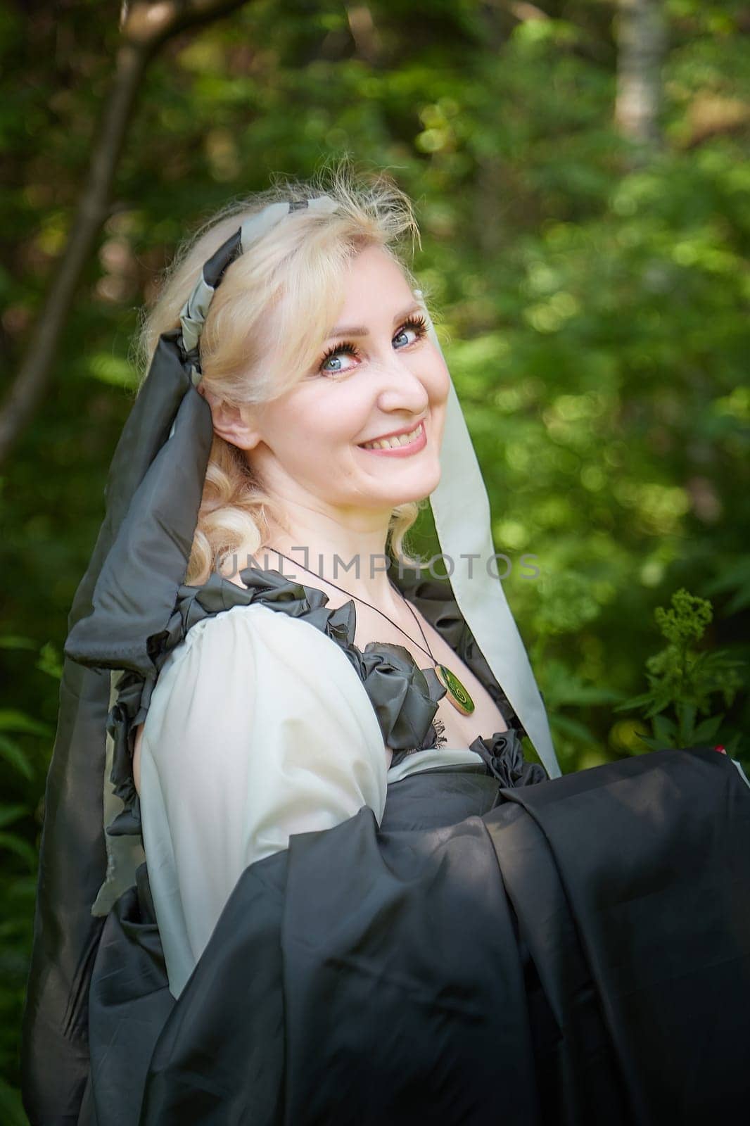 Adult mature woman 40-60 in a green long fairy dress in forest. Photo shoot in style of dryad and queen of nature. Fairy in beautiful green summer forest. Concept of caring for nature