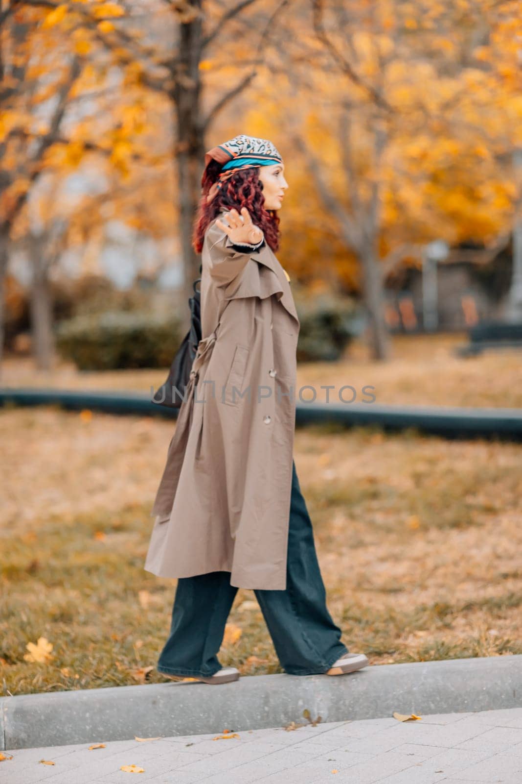 A woman walks outdoors in autumn, enjoys the autumn weather. by Matiunina