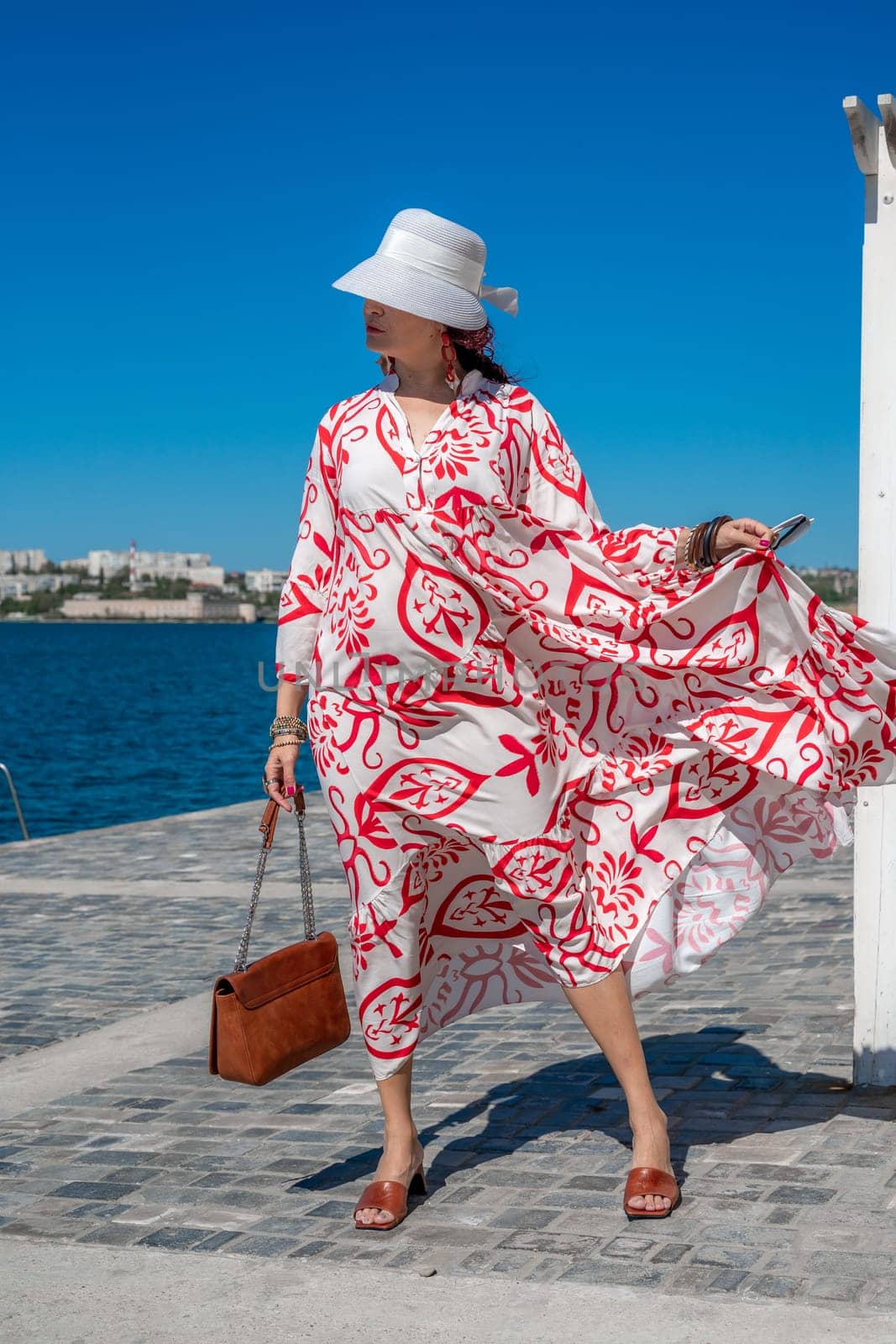 woman in a hat and dress enjoys the blue sea and summer. Welcome summer