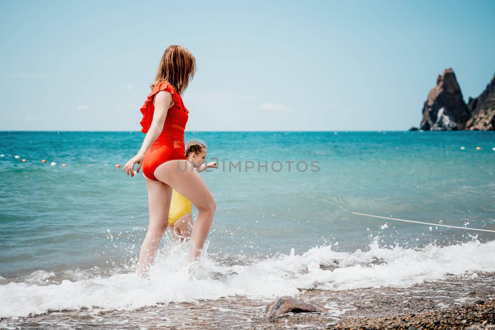 Happy loving family mother and daughter having fun together on the beach. Mum playing with her kid in holiday vacation next to the ocean - Family lifestyle and love concept.