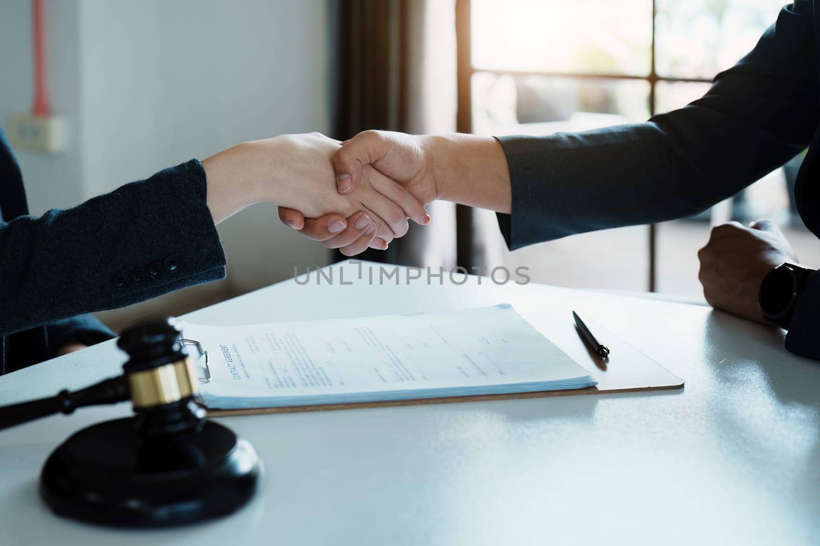 Law, consultation, agreement, contract, lawyer or attorney shakes hands to agree on the client's offer to be hired to fight the parties in court. by Manastrong