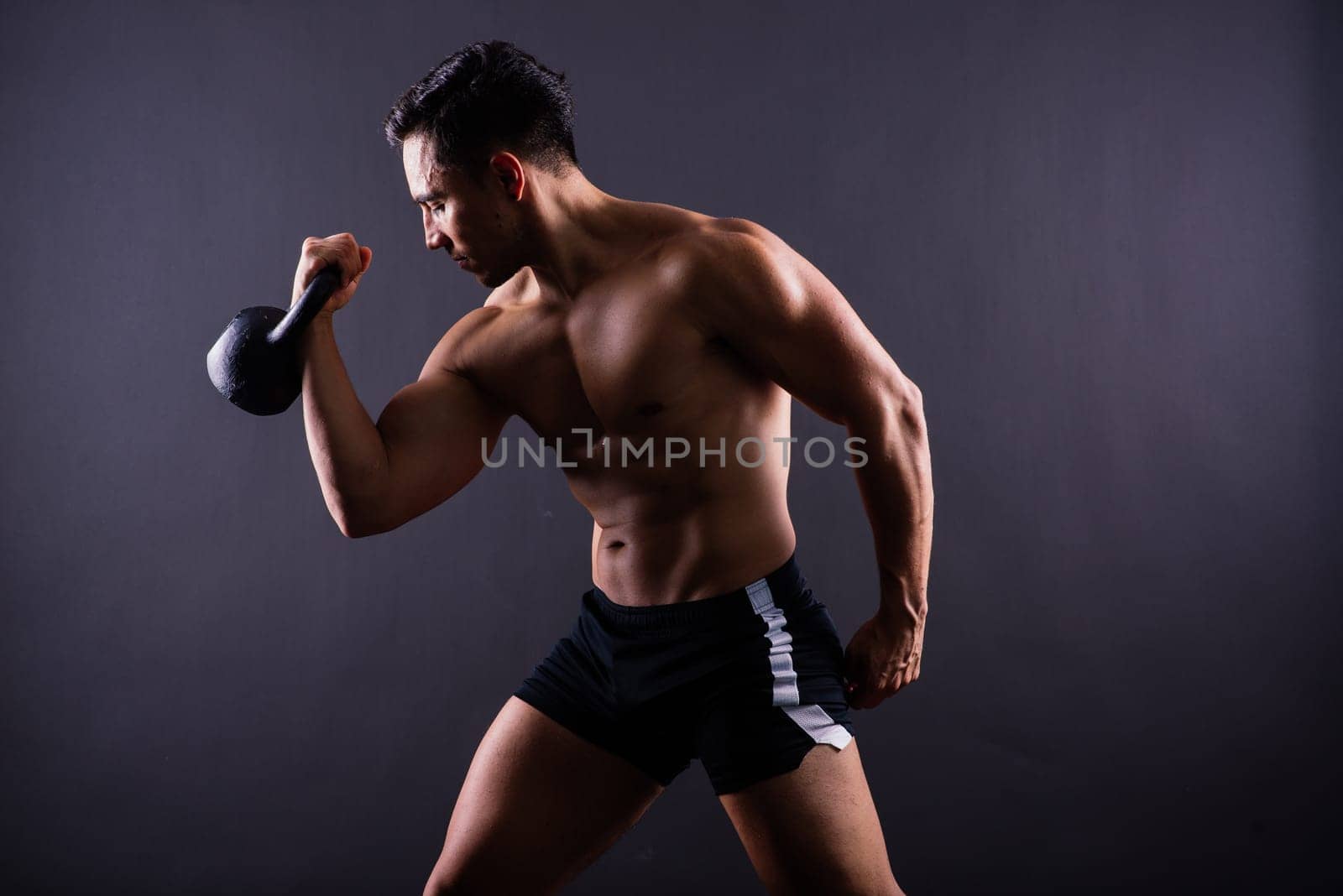 Hispanic male athlete working out with kettlebell on a grey background. Crossfit workout theme.