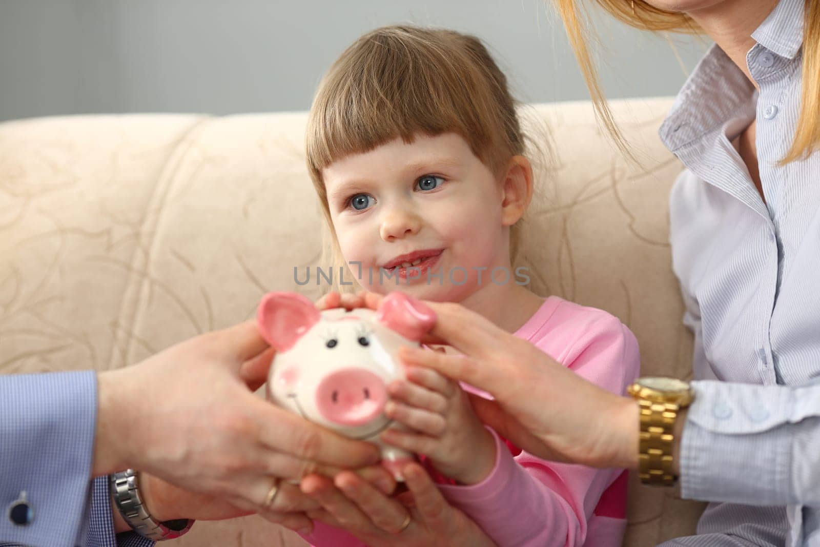 Young parents and little child girl are holding piggy bank by kuprevich