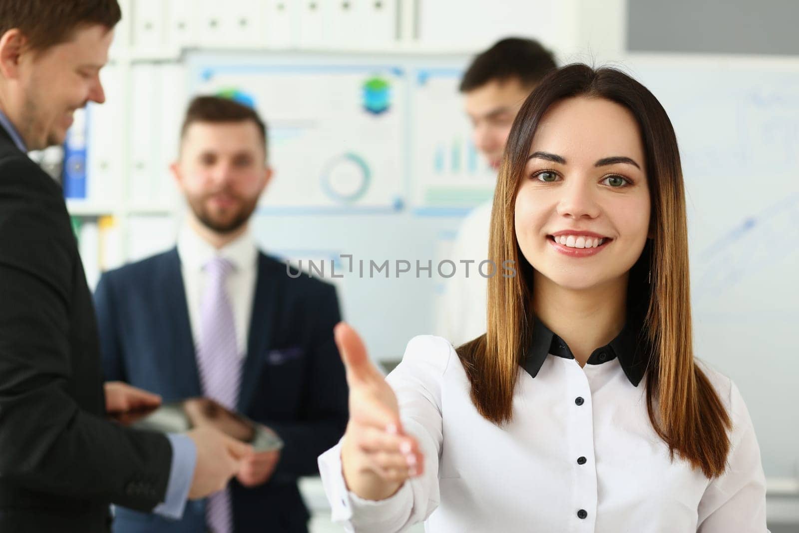 Businesswoman holds out hands for handshake and business team by kuprevich