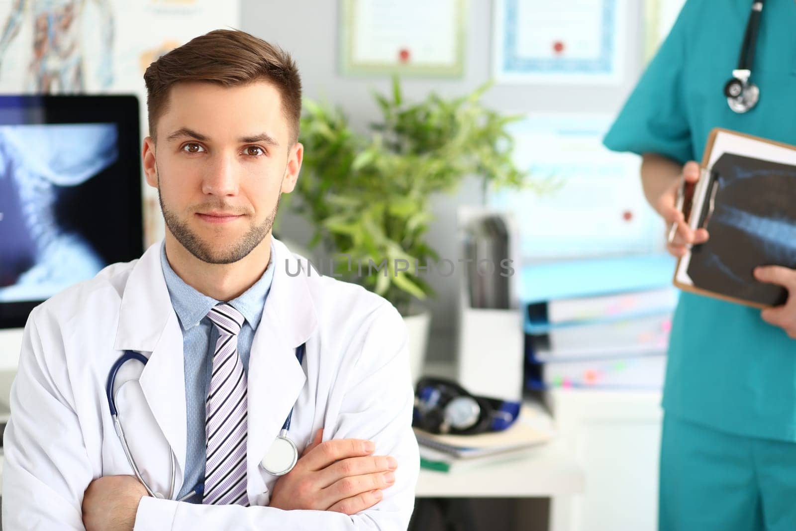 Portrait of young doctor in clinic with an assistant. Medical services and examinations of body concept