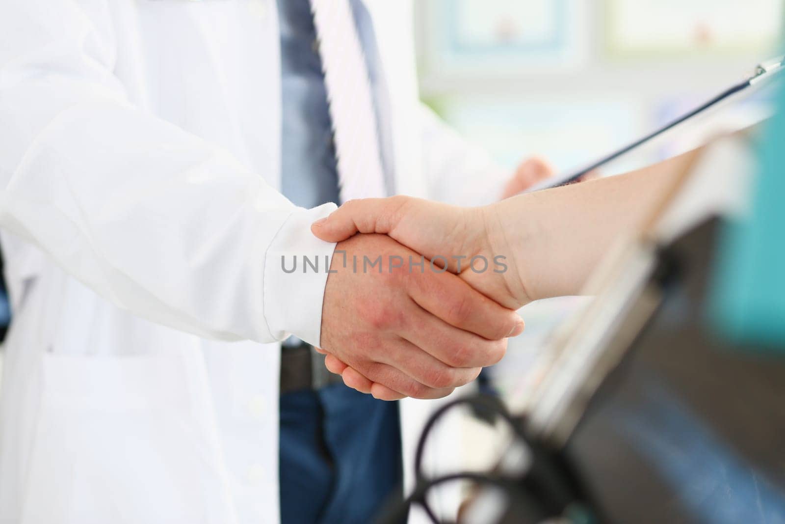 Doctor and patient shake hands in clinic. Medical care contract and insurance with handshake