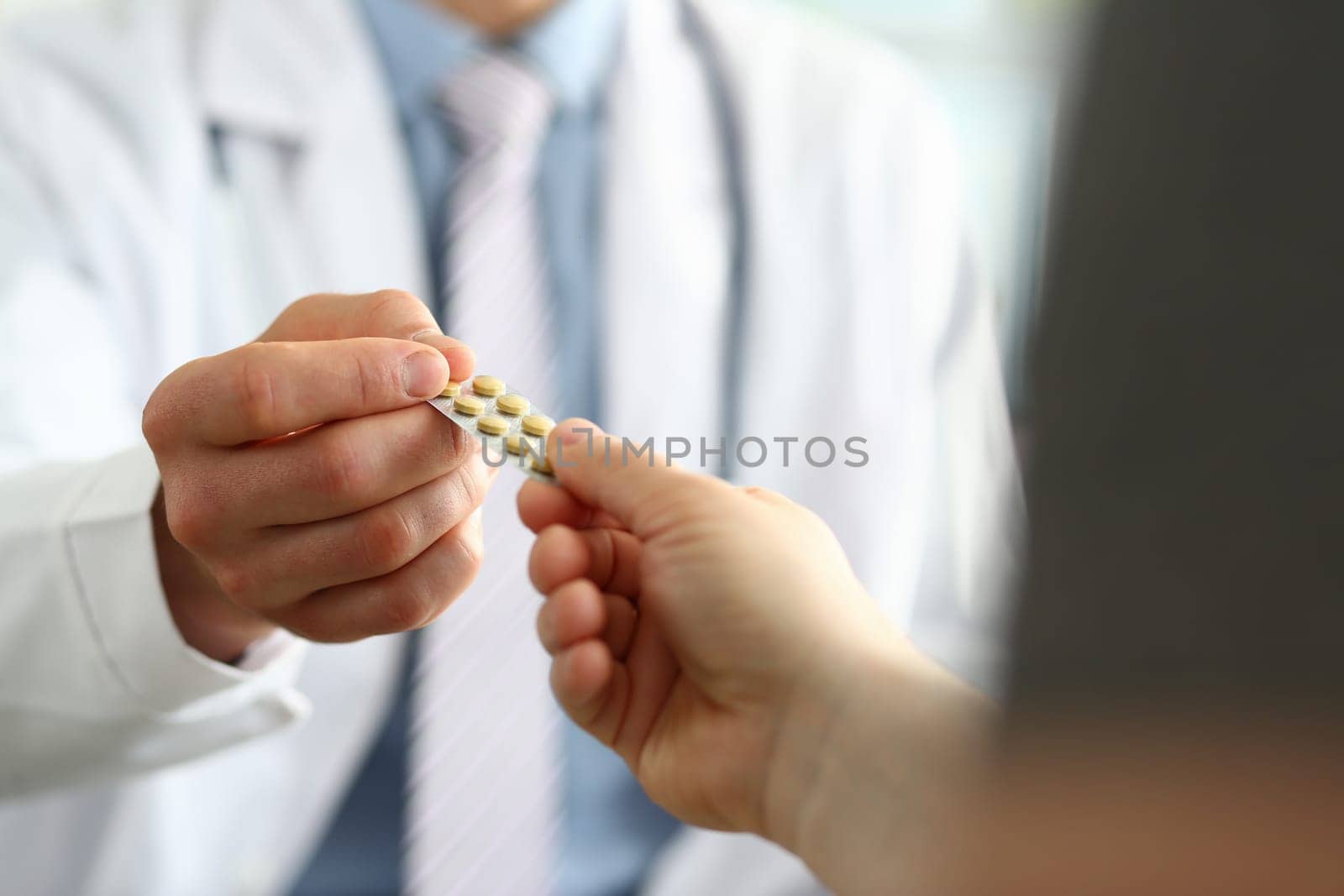 Closeup of doctor hand giving medical pills to patient by kuprevich