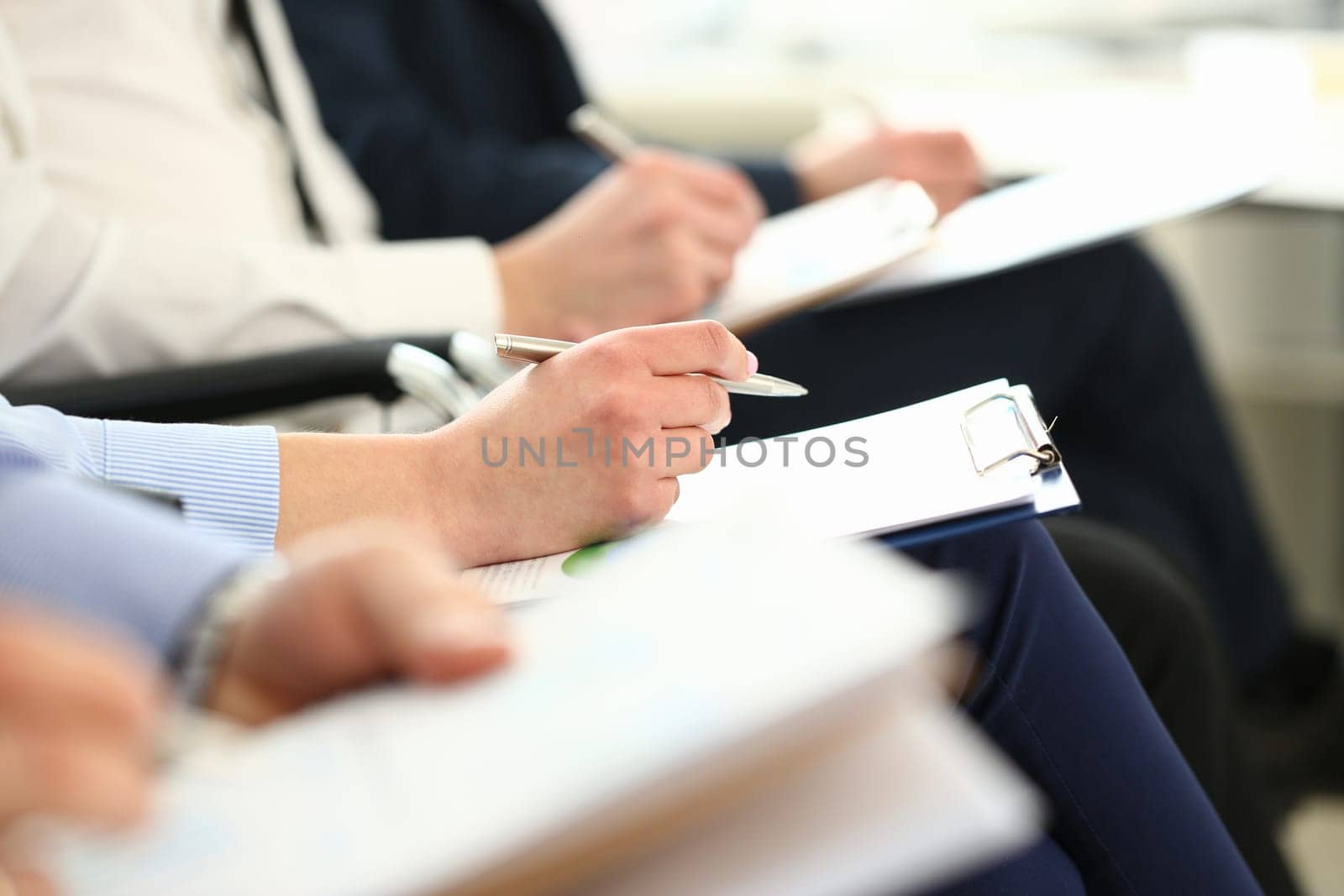 Businessmen are holding documents while taking notes at seminar by kuprevich