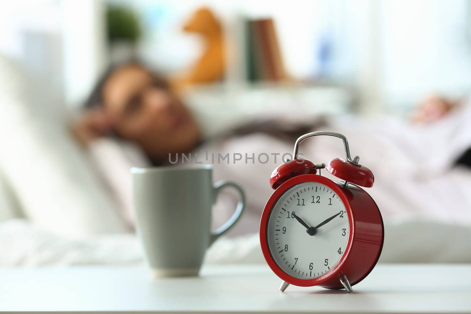 Red alarm clock at ten o'clock and sleeping woman by kuprevich