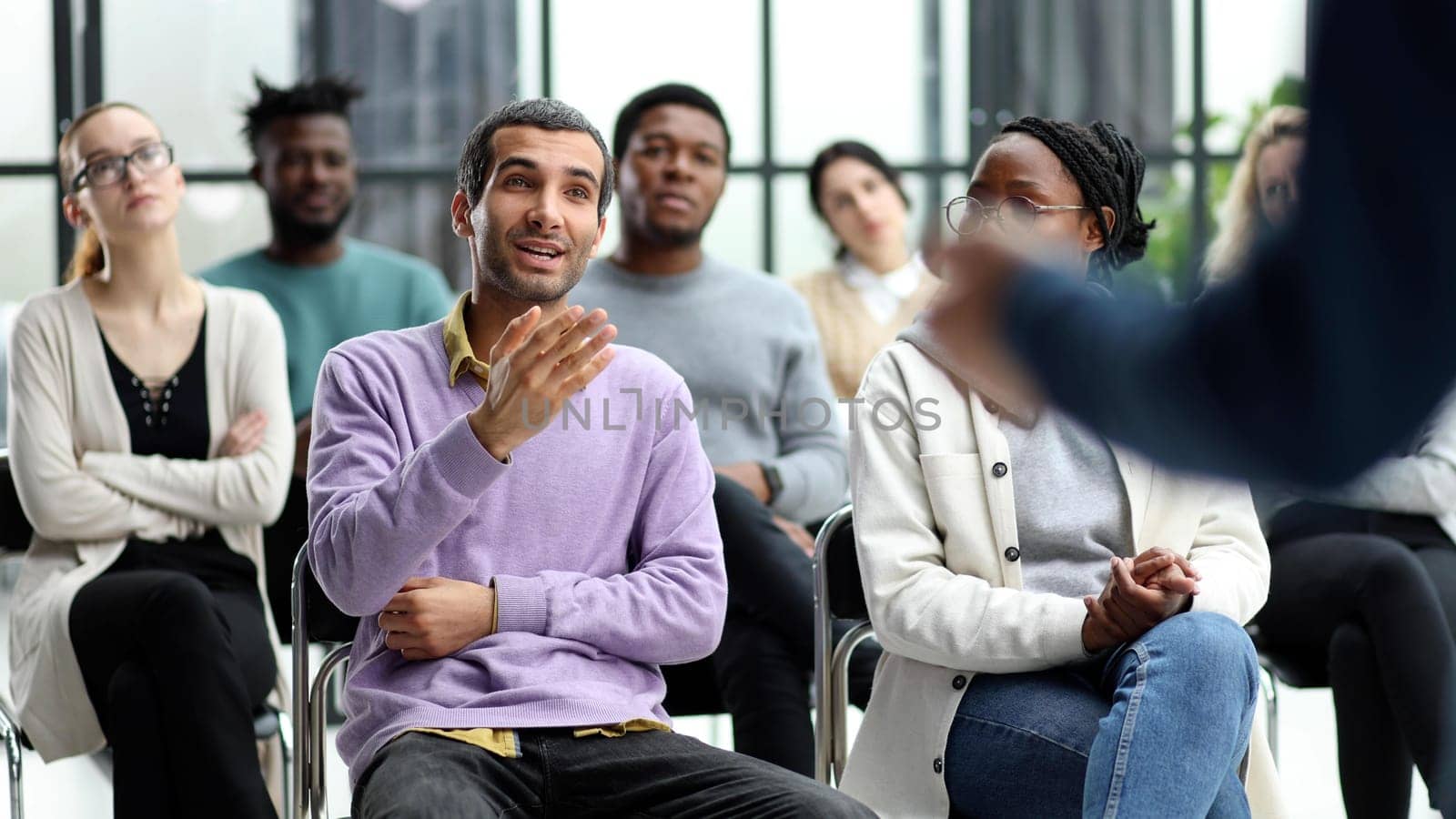 speaker addresses people sitting on chairs in a conference room