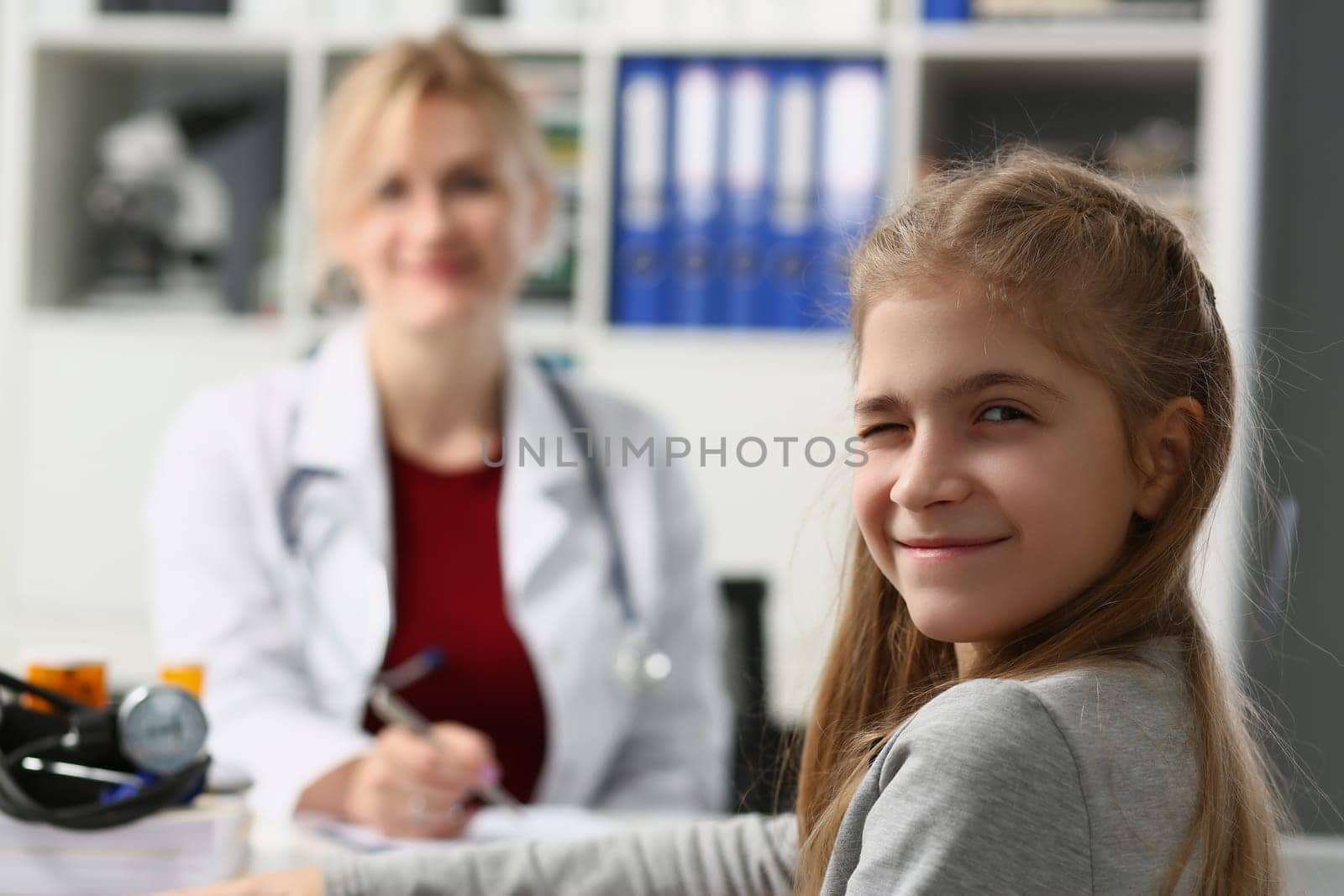 Portrait of child girl winks at camera in doctor office by kuprevich