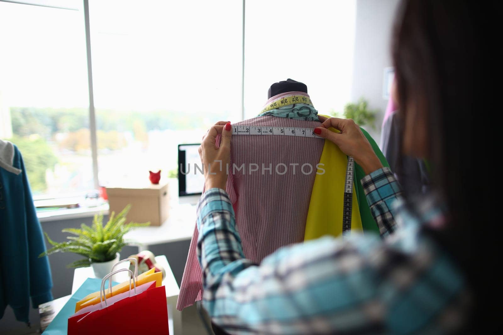 Woman fashion designer seamstress stylist measuring mannequin with tape. Working with mannequin in cozy creative design studio or atelier concept