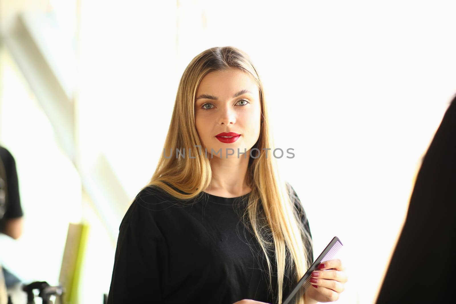 Portrait of beautiful young woman hairdresser with comb. Training profession stylist and fashion hairdresser