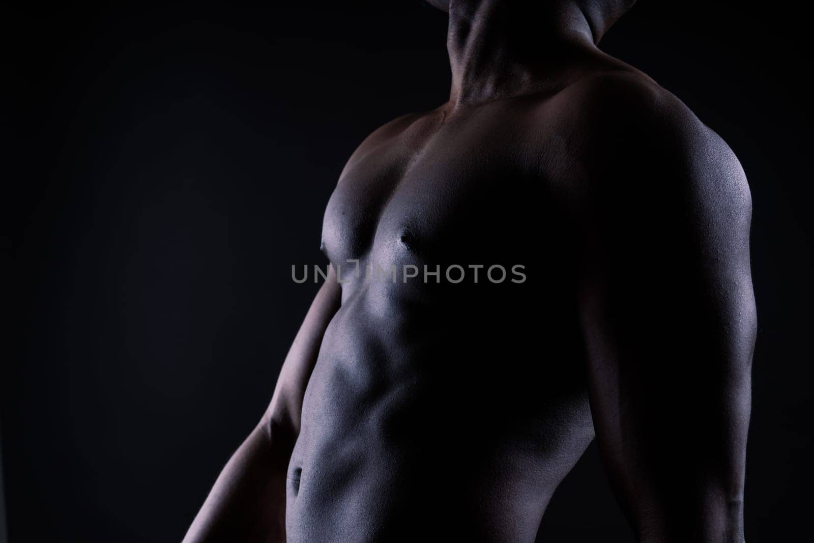 Athletic african american man topless, big muscles, a dark background studio