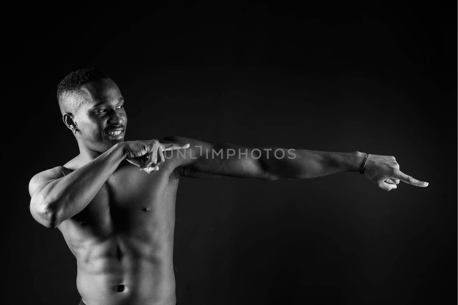 Athletic african american man topless, big muscles, a dark background studio