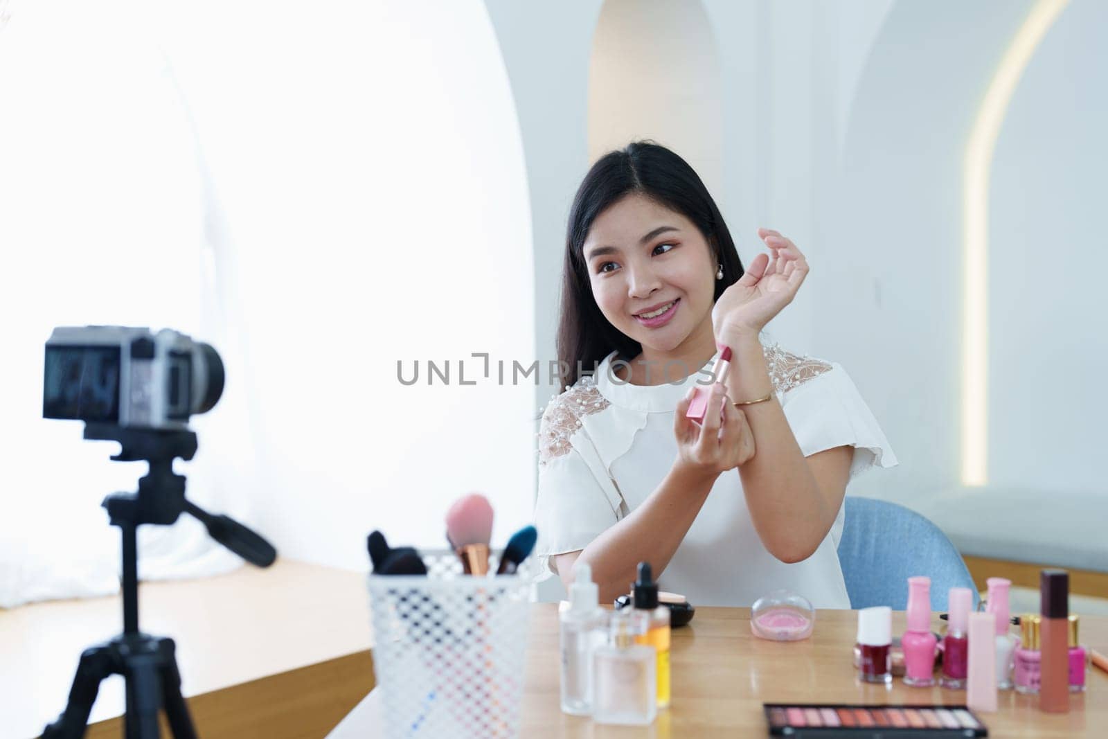 online trading business, a beautiful young woman working independently at home reviewing cosmetic products through the camera to customers to increase their interest in making a purchase decision by Manastrong