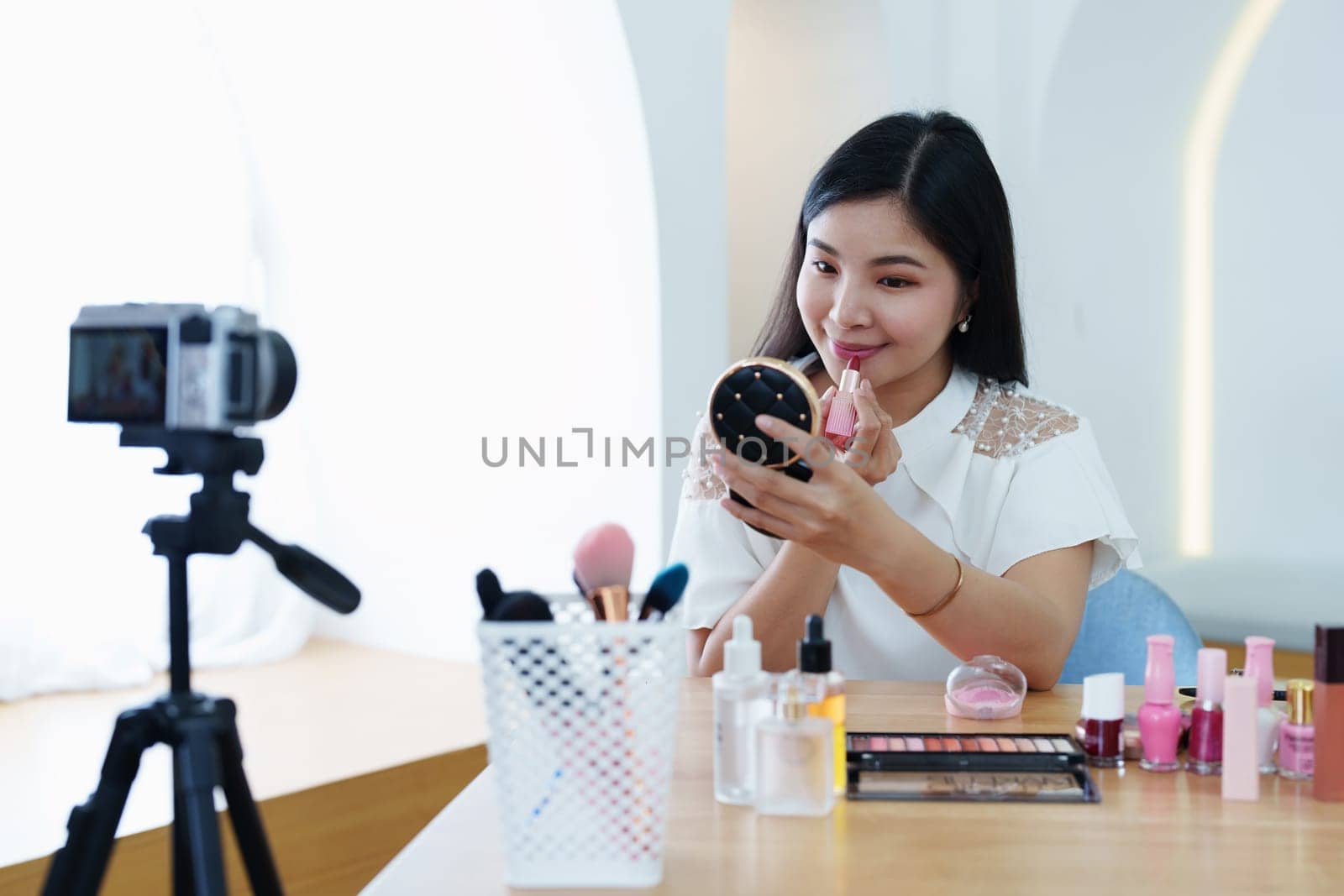 online trading business, a beautiful young woman working independently at home reviewing cosmetic products through the camera to customers to increase their interest in making a purchase decision.