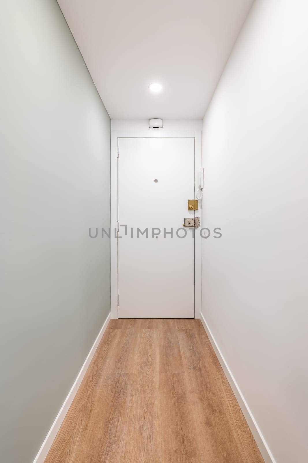 White corridor with entrances to a bright room and doors in an empty apartment before moving or after renovation. Concept of renovation and moving into compact new apartment. Copyspace.