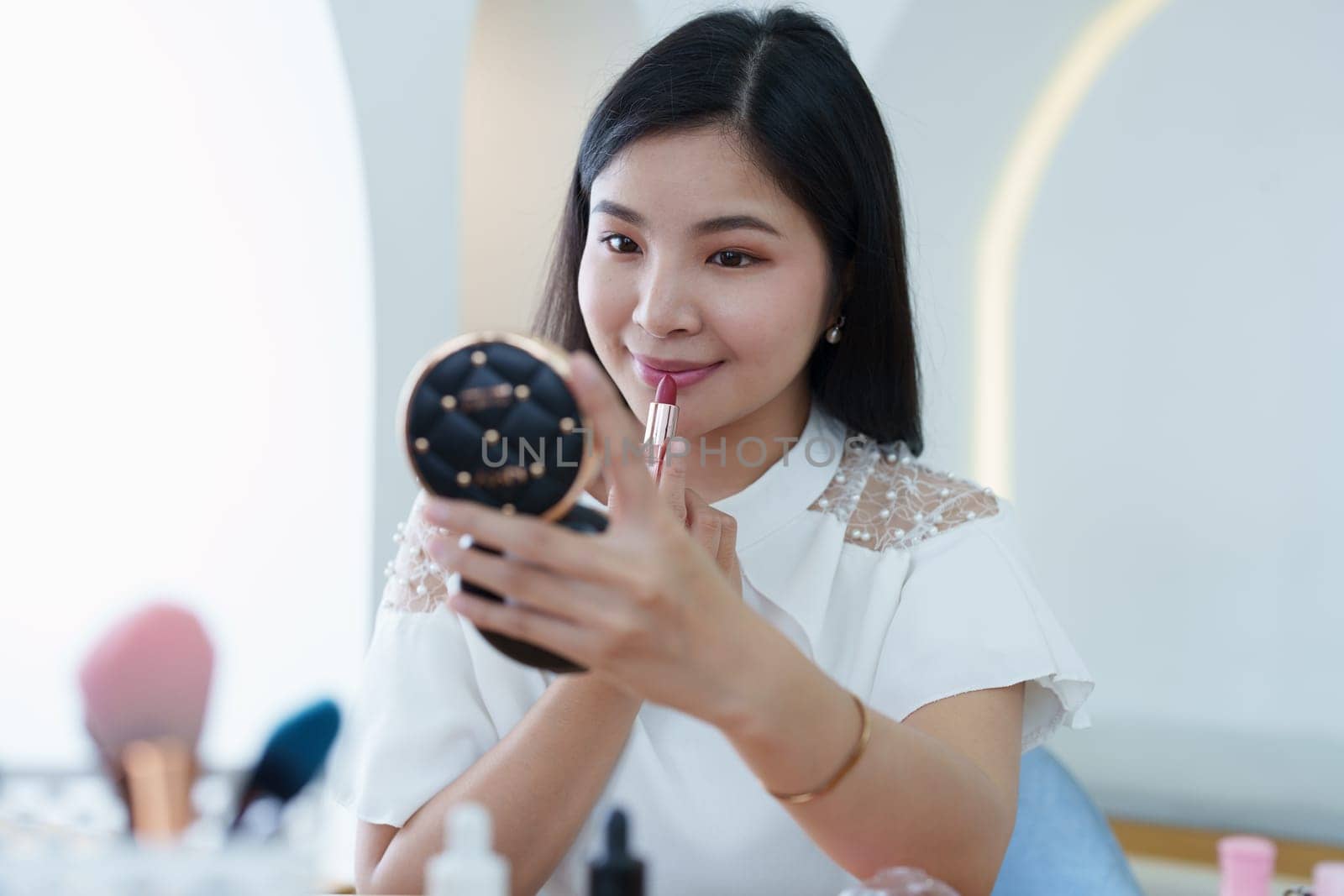 online trading business, a beautiful young woman working independently at home reviewing cosmetic products through the camera to customers to increase their interest in making a purchase decision by Manastrong