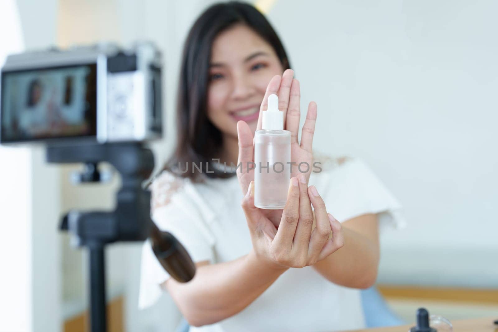 online trading business, a beautiful young woman working independently at home reviewing cosmetic products through the camera to customers to increase their interest in making a purchase decision.