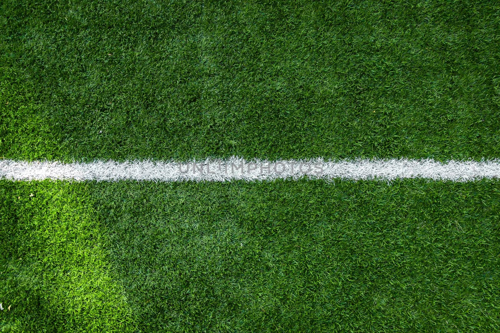 White stripe markings on the green grass of the soccer field, copy space background.