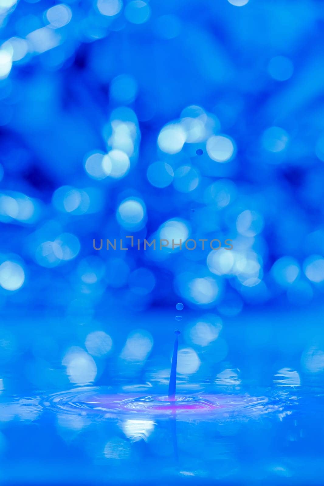 A drop falls into a thick liquid with a blue-pink background. Abstract colorful background