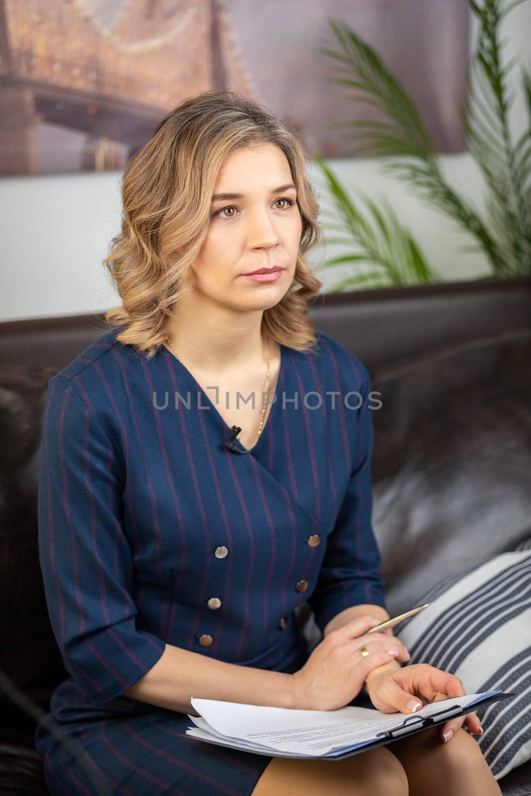 Portrait of a successful female psychologist in her office, notebook in hand, on the couch