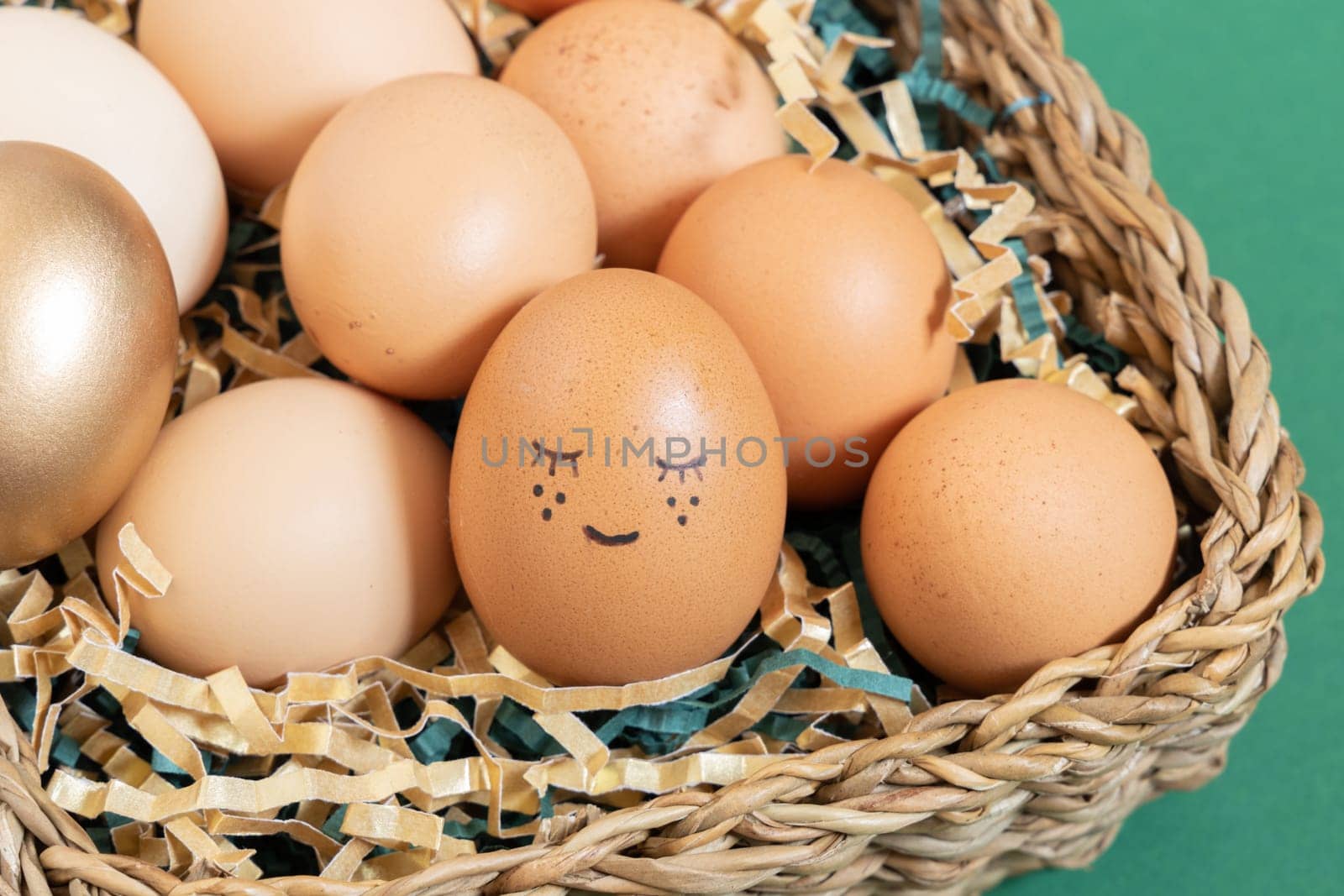 Close up of easter eggs with funny face natural and gold in basket with paper filler by Ri6ka