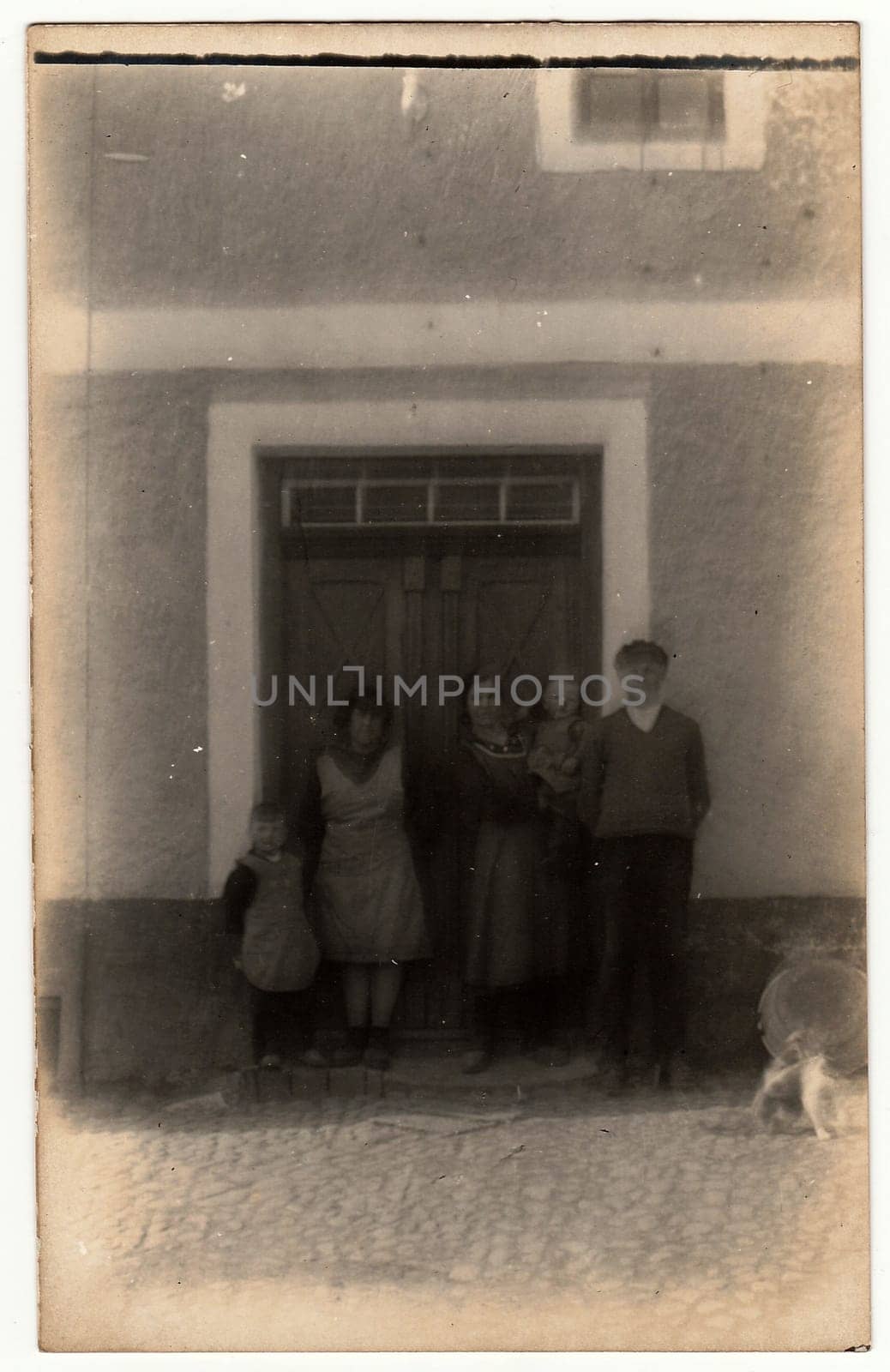 Vintage photo shows a rural family in front of house. Photography contains slight blurriness. by roman_nerud