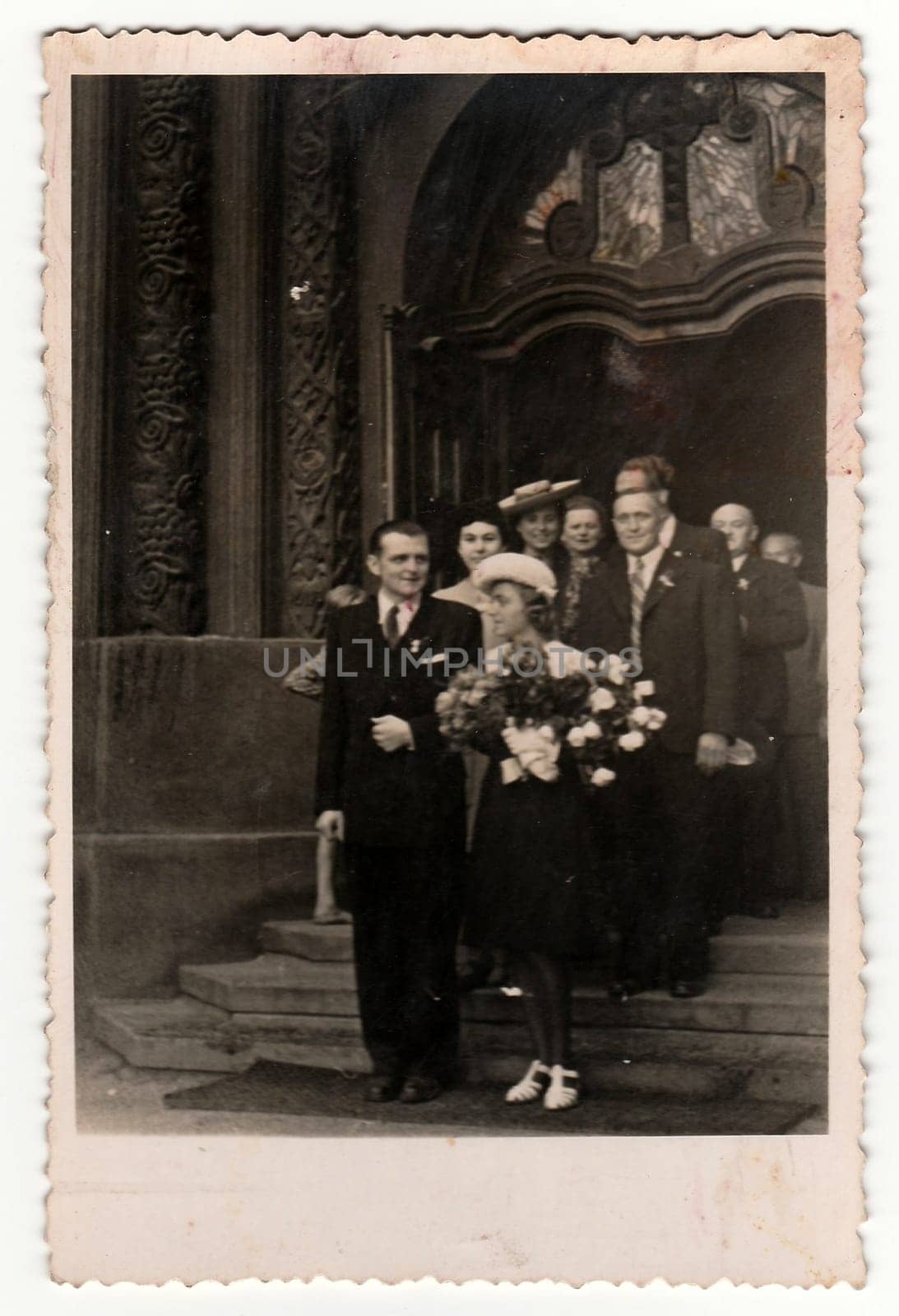 Retro photo shows the newlyweds and wedding guests on stairs of cathedral church . Black white photography. by roman_nerud