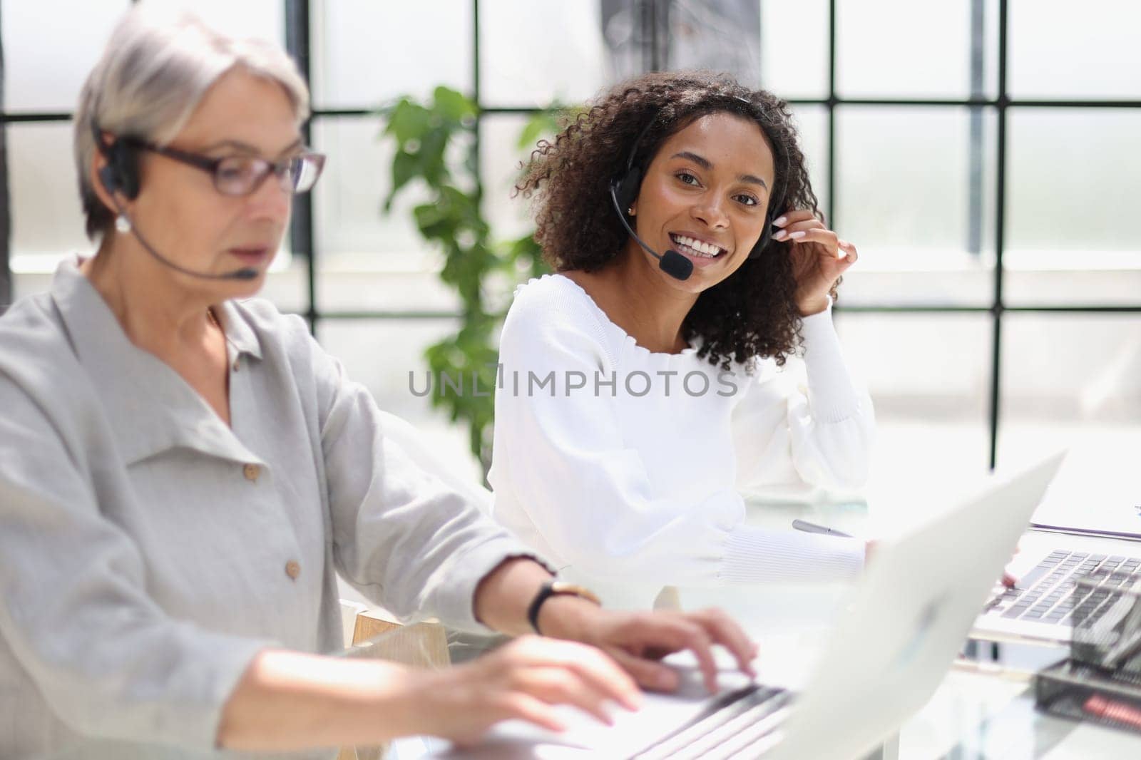 Young friendly operator woman agent with headsets working in a call centre