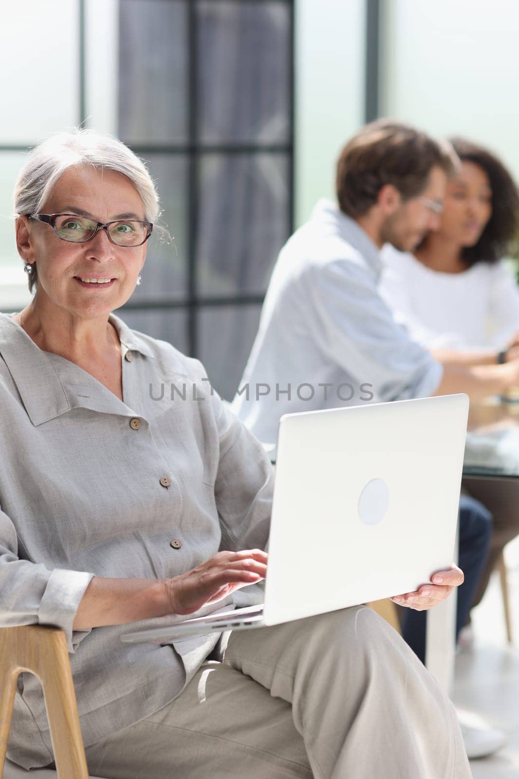 mature woman sitting with laptop looking at camera.