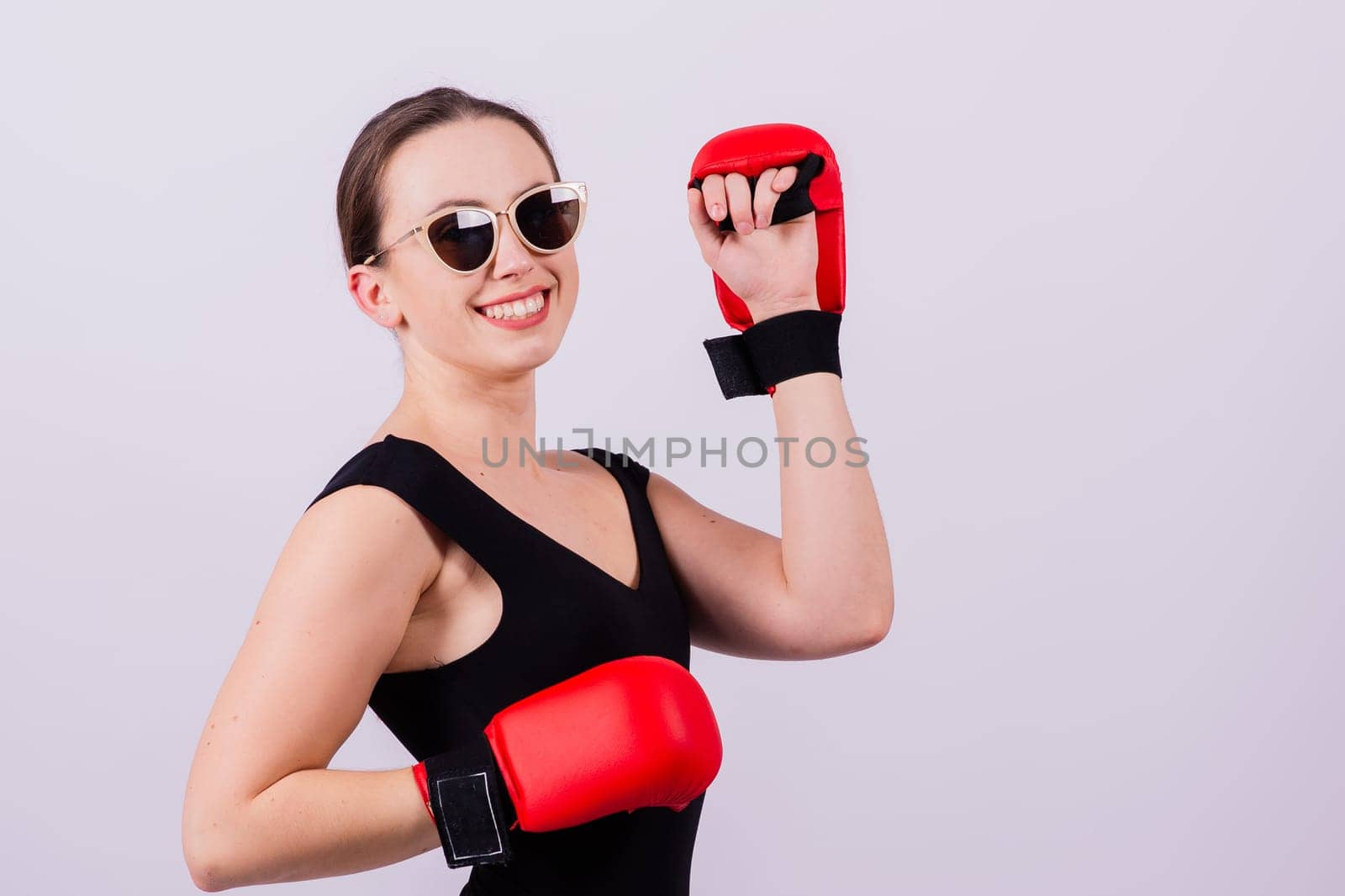 Seductive female boxer with athletic beautiful figure in black swimsuit gloves on gray background by Zelenin