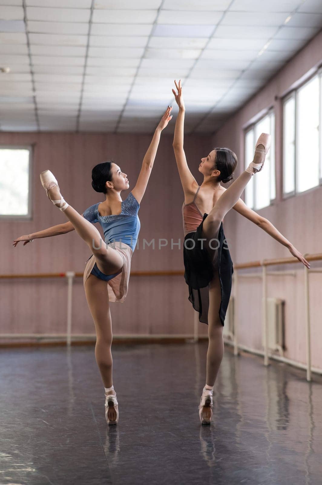 Two Asian ballerinas are dancing in the class