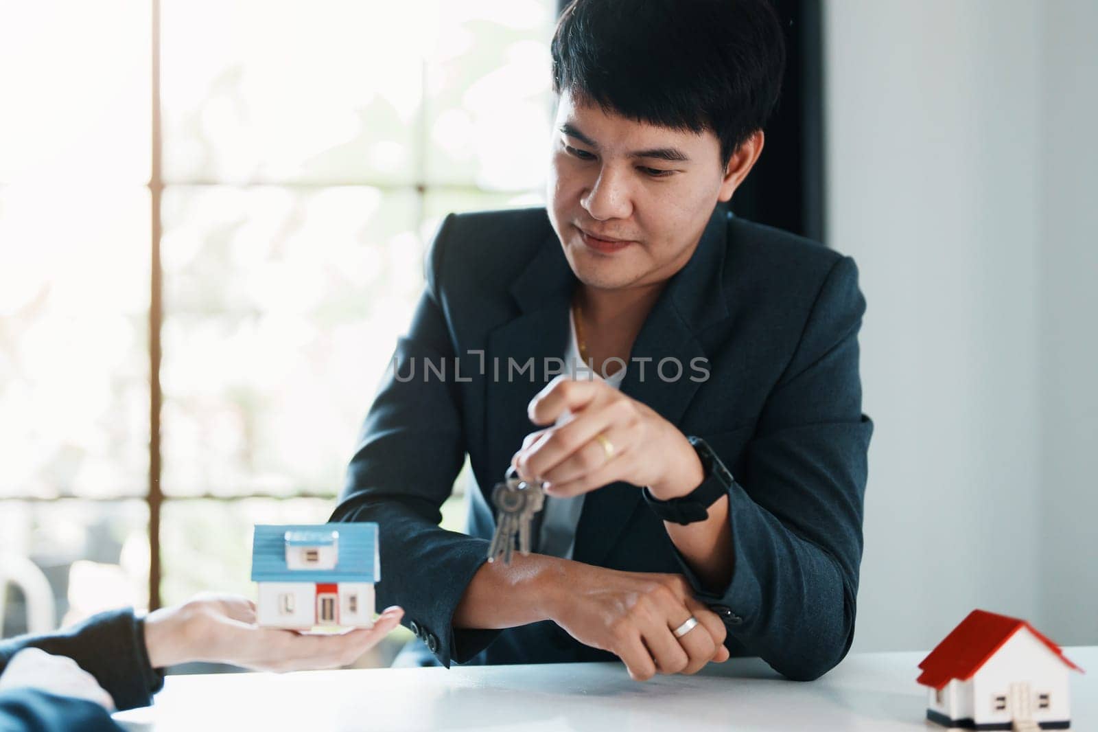 Accountant, businessman, real estate agent, Asian business woman handing keys to customers along with house after customers to sign by Manastrong