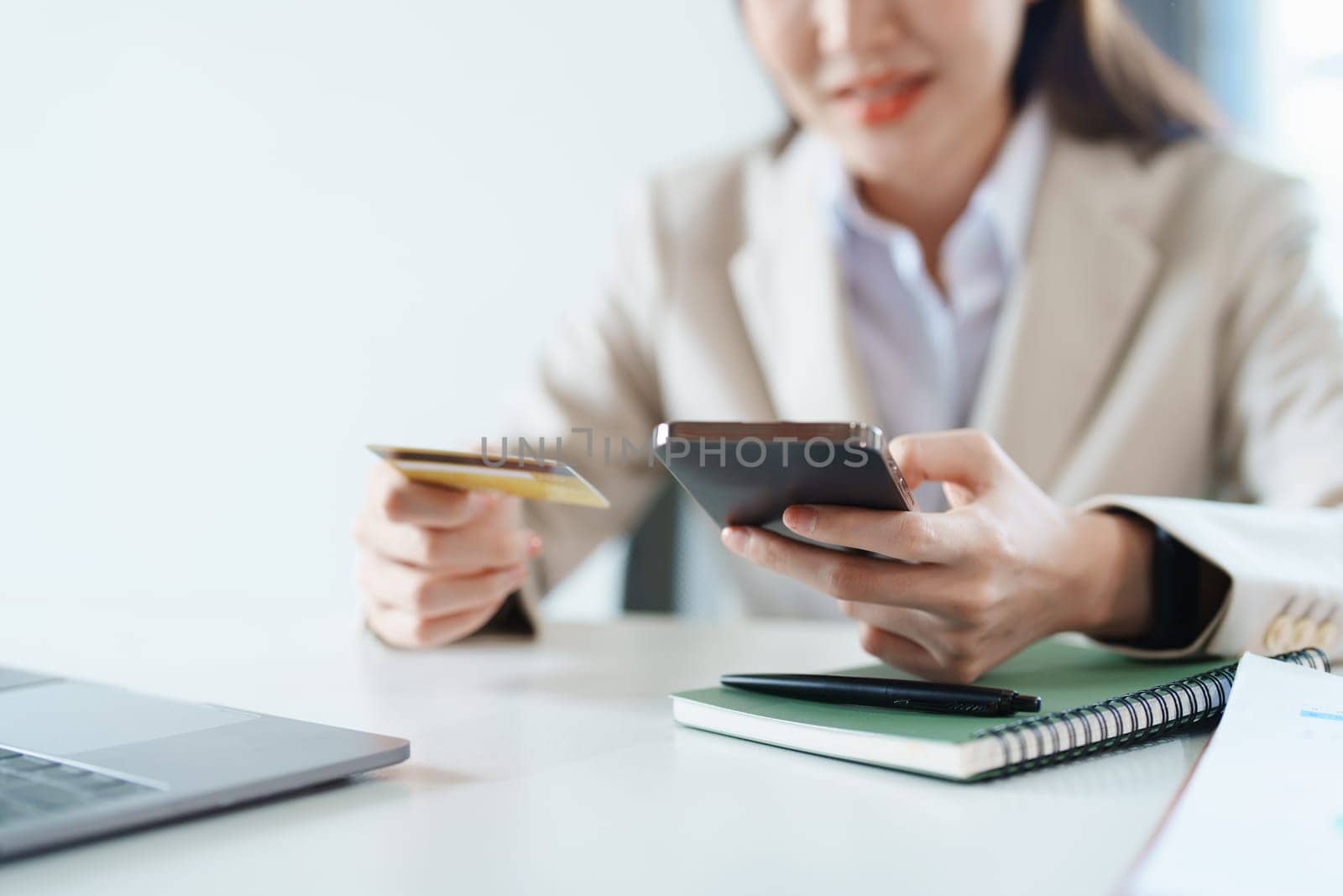 Portrait of young Asian woman using credit card and phone for online shopping by Manastrong