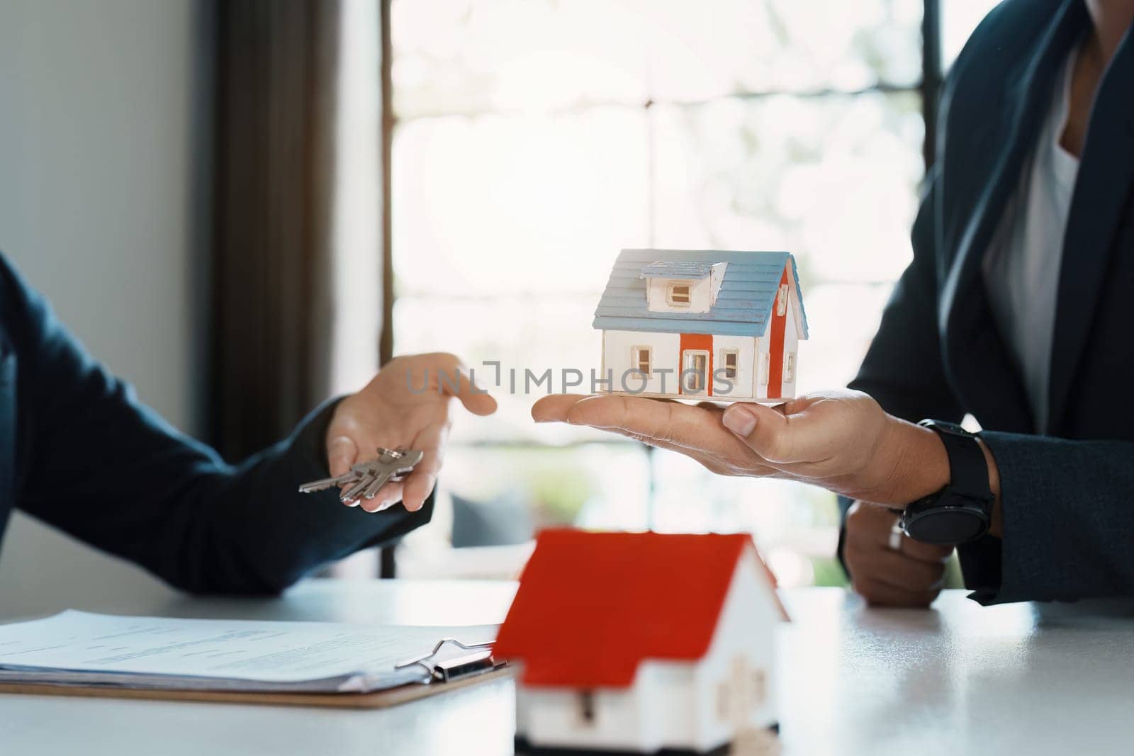 Accountant, businessman, real estate agent, Asian business woman handing keys to customers along with house after customers to sign by Manastrong