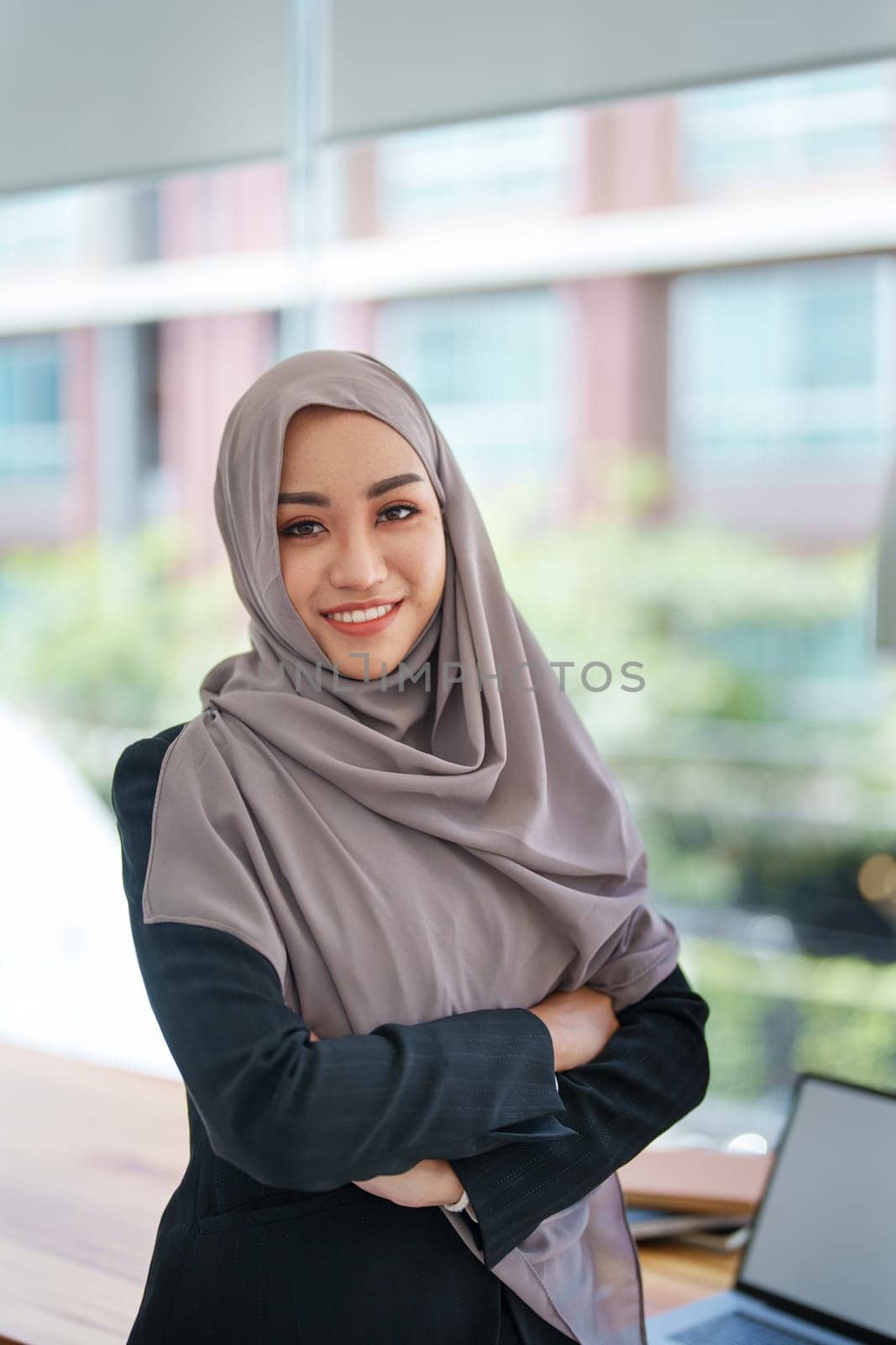 A beautiful Muslim woman showing a smiling face in the morning using computers and documents working at the office.