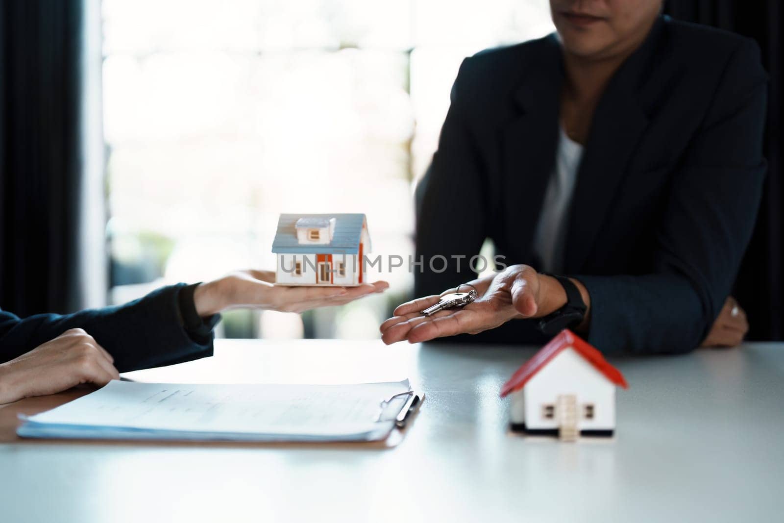 Accountant, businessman, real estate agent, Asian business woman handing keys to customers along with house after customers to sign by Manastrong