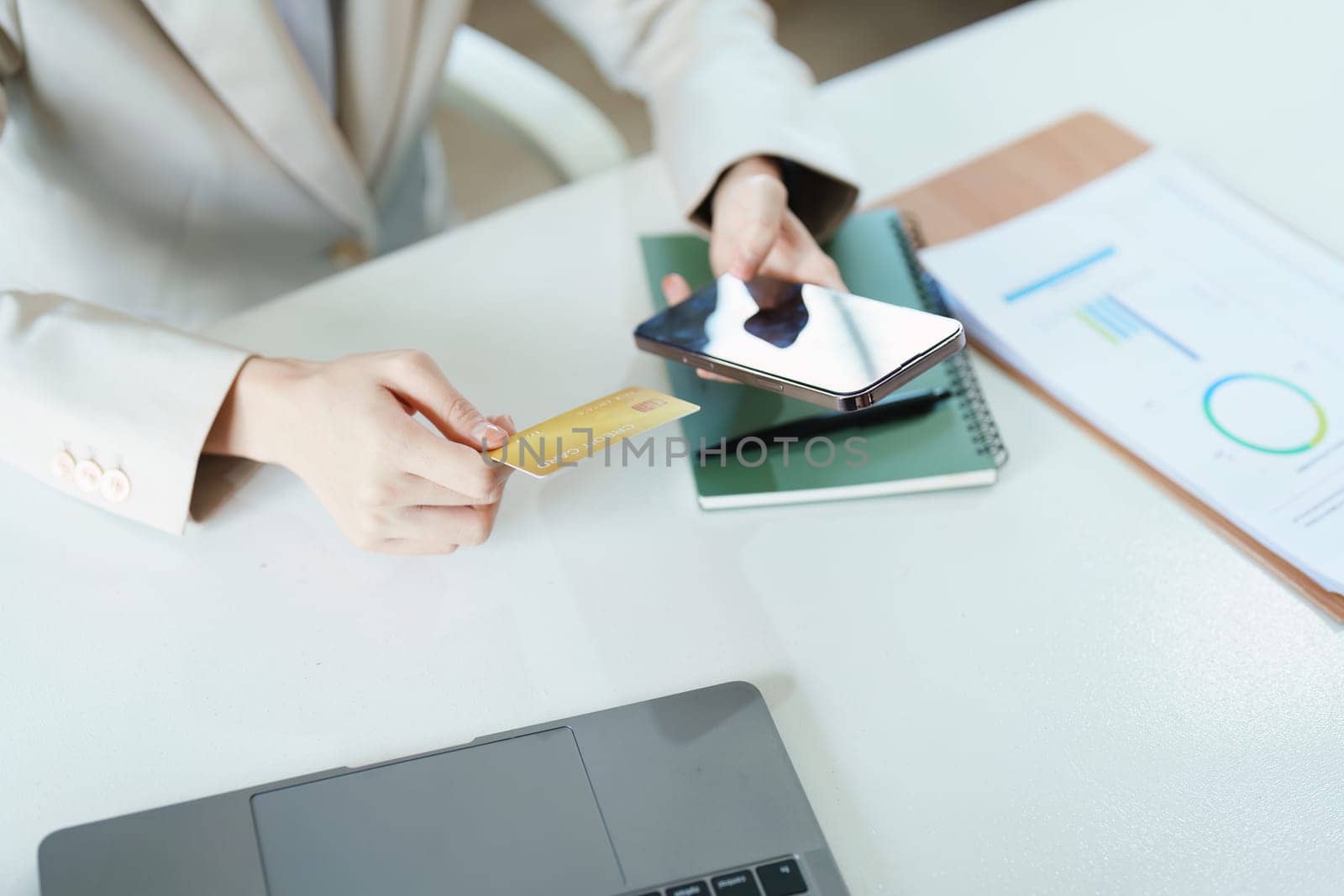 Portrait of young Asian woman using credit card and phone for online shopping by Manastrong