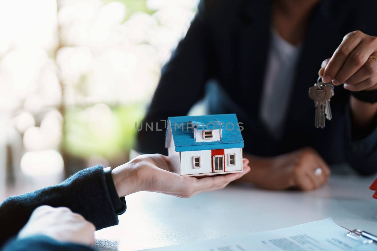 Accountant, businessman, real estate agent, Asian business woman handing keys to customers along with house after customers to sign by Manastrong