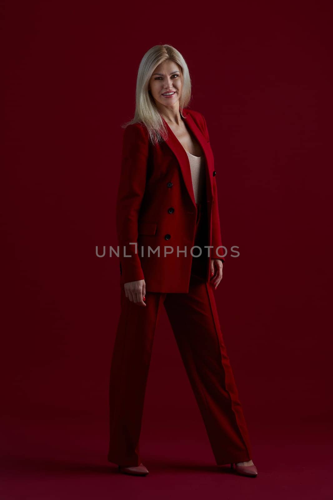 Portrait of a blonde woman in red dress on a red background