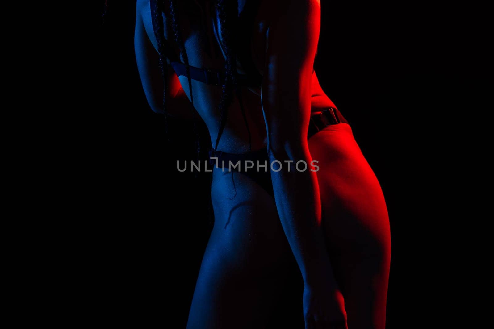 Young woman in underwear is in a studio with neon lights.