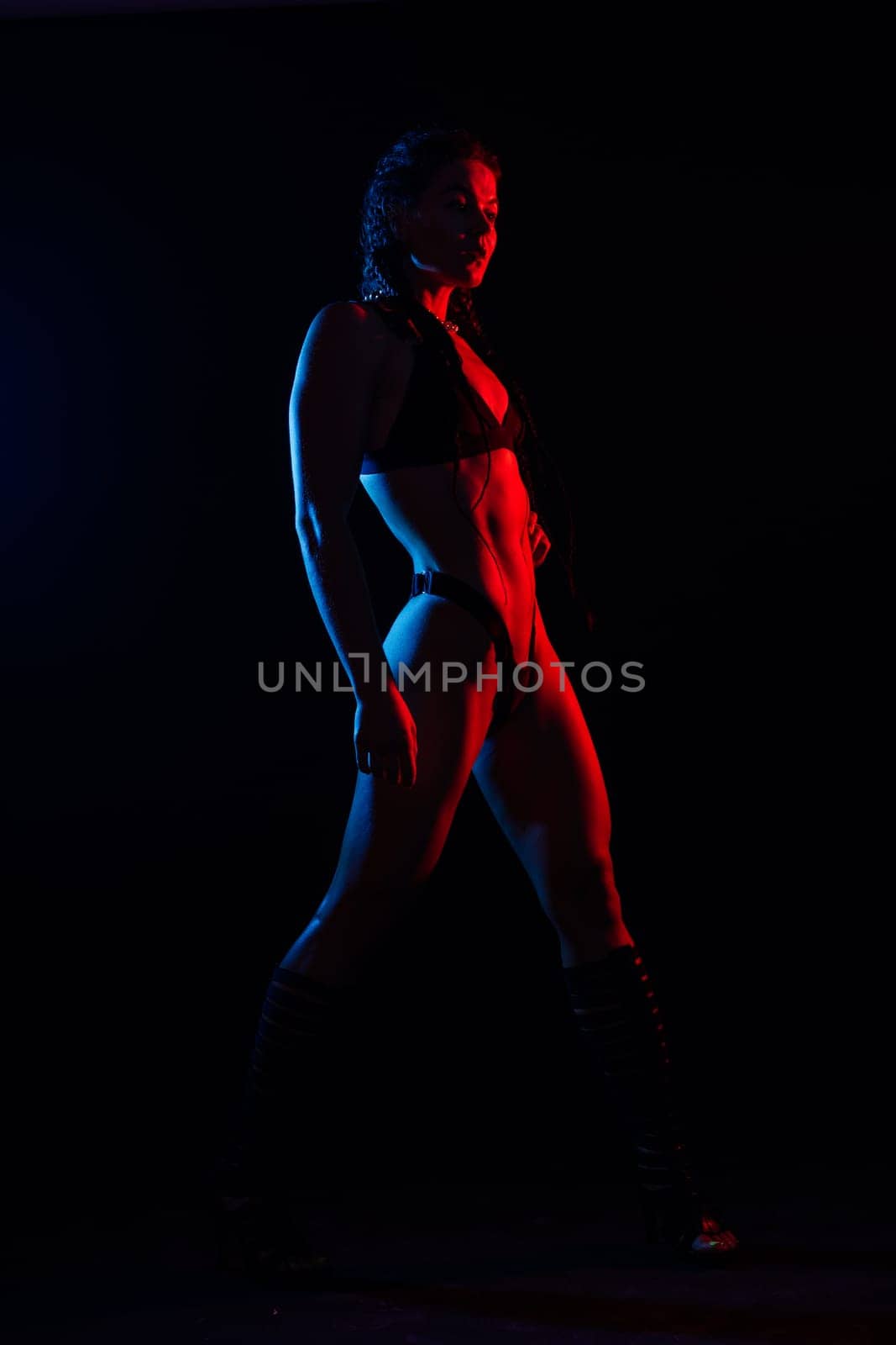 Young woman in underwear is in a studio with neon lights.