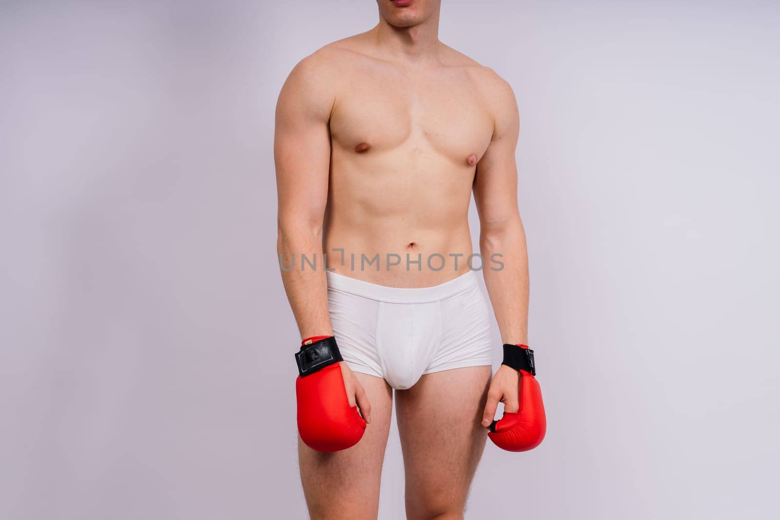 Bodybuilders boxing gloves on a white background and white pants athlete model